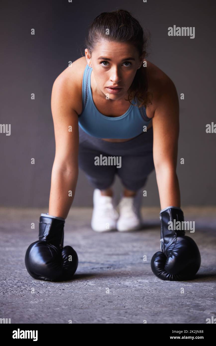 Entscheiden Sie sich für den Schmerz der Disziplin oder des Bedauerns. Porträt einer jungen Frau, die beim Training Boxhandschuhe trägt. Stockfoto
