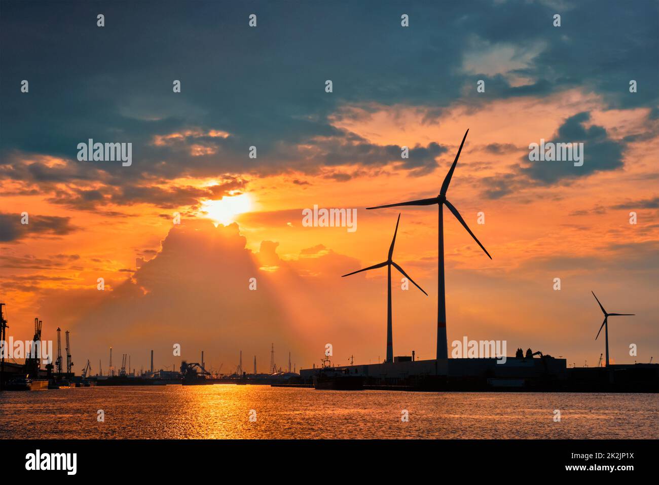 Windturbinen im Hafen von Antwerpen bei Sonnenuntergang. Stockfoto