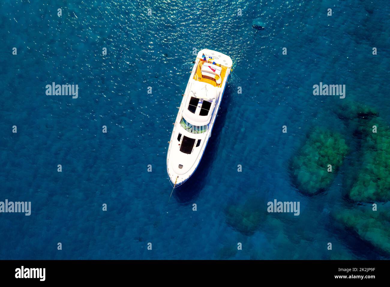 Blick von oben auf das weiß-gelbe Boot auf blauem Wasser Stockfoto