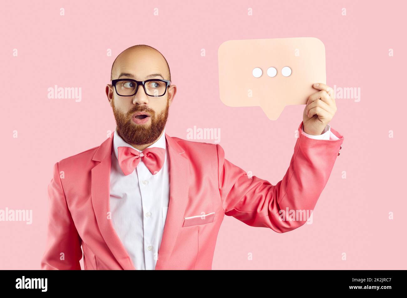 Lustiger Mann, der eine Nachrichtenblase mit drei Punkten hält, die zeigen, dass jemand eine Antwort tippt Stockfoto