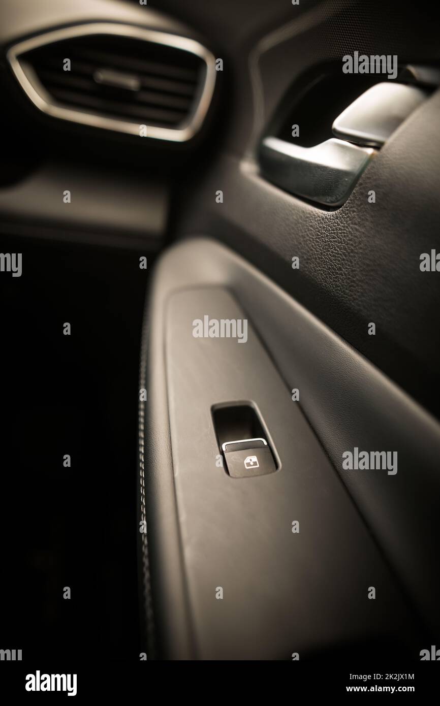 Schwarzer Knopf zum Aufrichten der Autoscheibe in der Autotür. Stockfoto