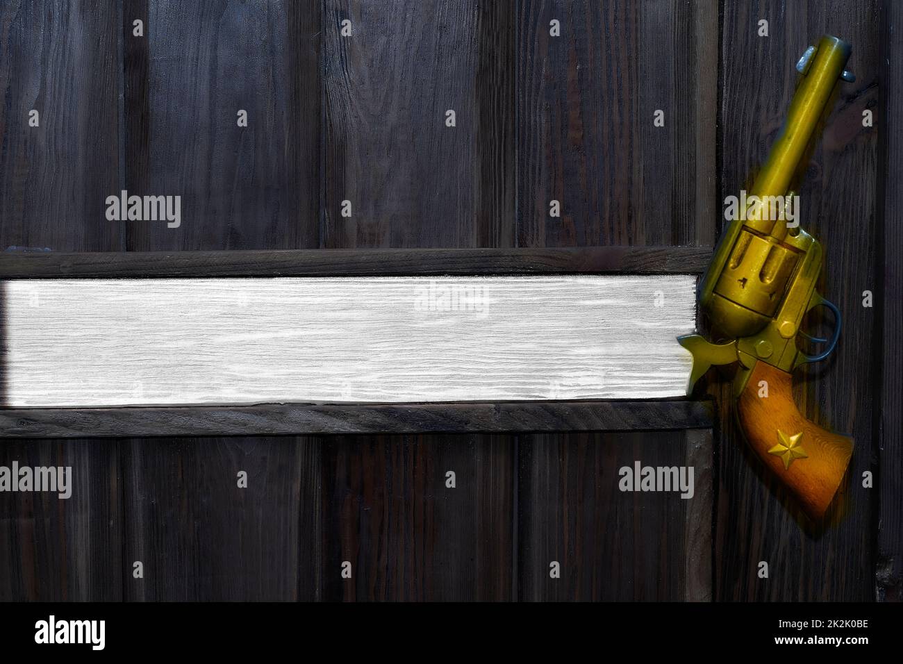 Cowboy Gold Revolver auf einer schwarzen Holzwand. Platz für Text. Das Büro des Chefs Stockfoto