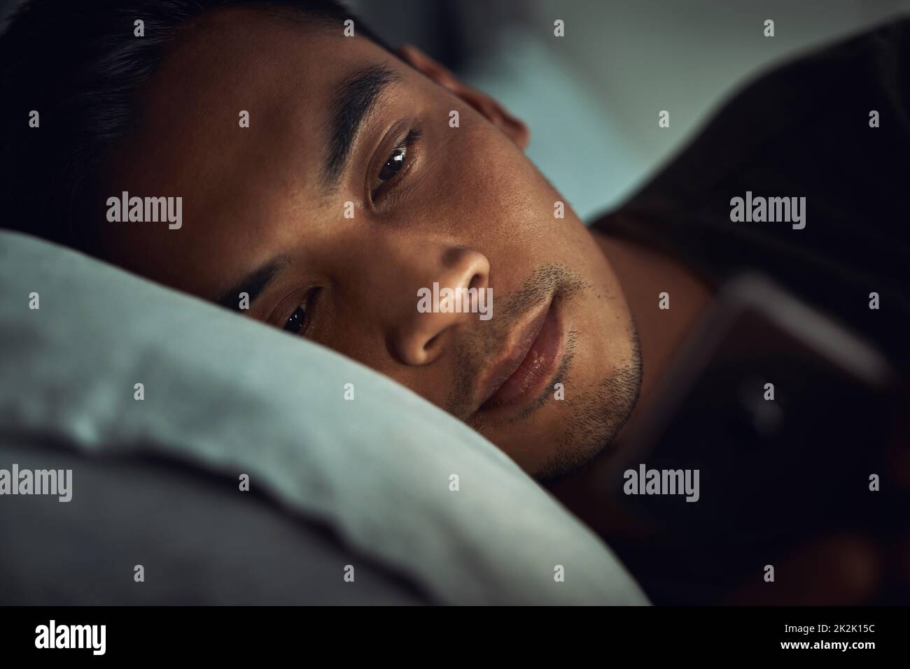 So viel, um heute Abend früh ins Bett zu gehen. Aufnahme eines jungen Mannes, der zu Hause im Bett liegt und ein Smartphone benutzt. Stockfoto