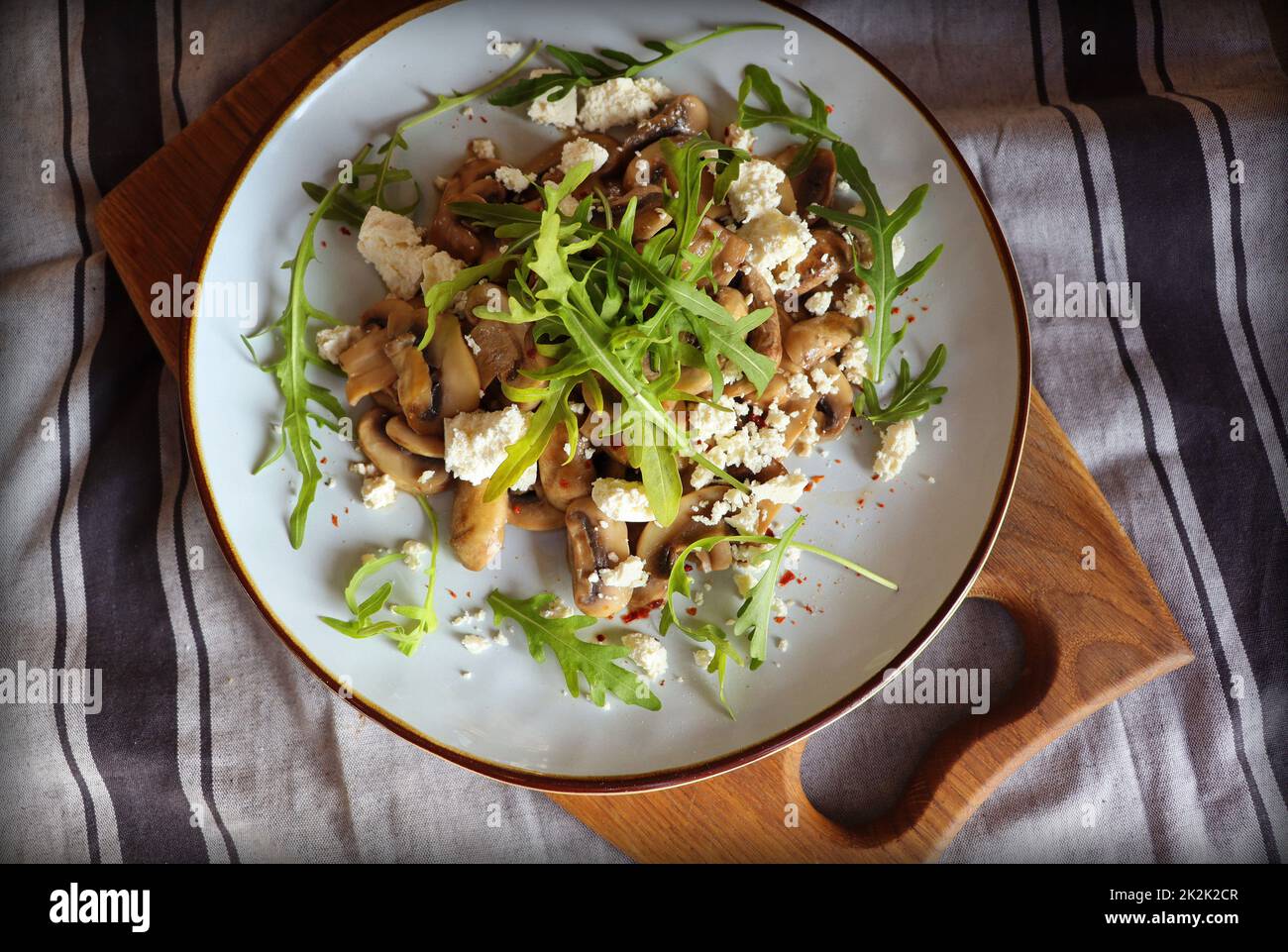 Warmer Pilzsalat mit Feta-Käse und Rucola auf einer Leinenserviette Stockfoto