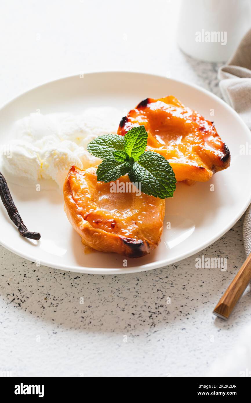 Apfelquitte mit Honig auf einem weißen Teller mit Eis gebacken. Gesundes vegetarisches Dessert. Stockfoto