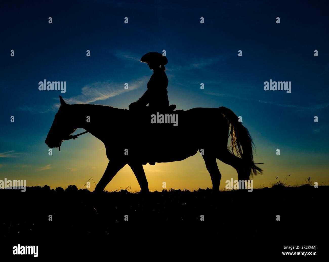 Silhouette Cowgirl auf Pferd bei Sonnenaufgang Stockfoto