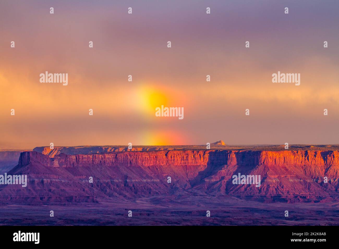 Sturm mit einem Regenbogen über Hatch Point Mesa. Blick vom Buck Canyon Overlook im Canyonlands National Park, Moab, Utah. Stockfoto