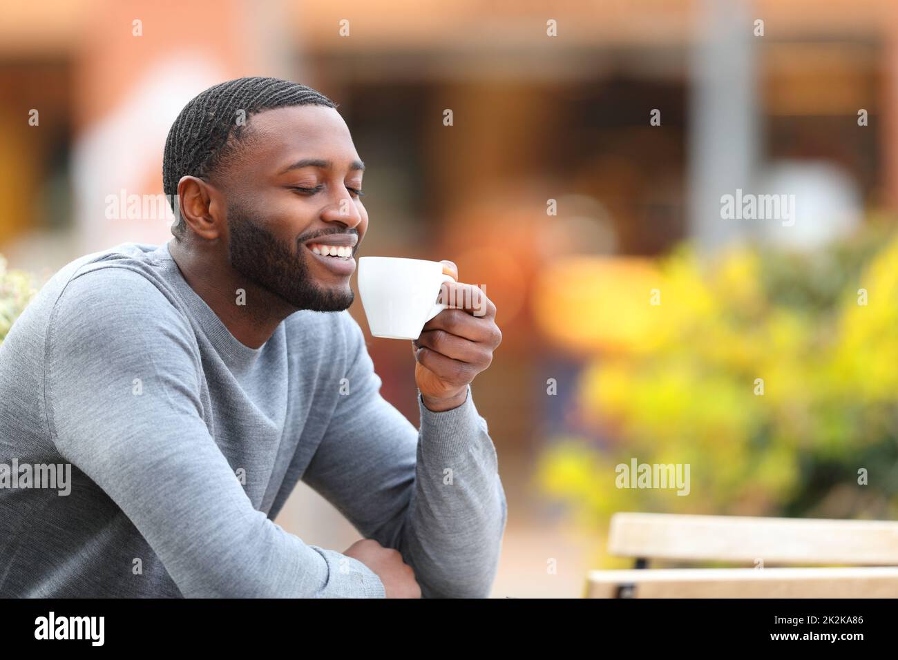 Glücklicher Mann mit schwarzer Haut, der Kaffee in einer Bar trinkt Stockfoto