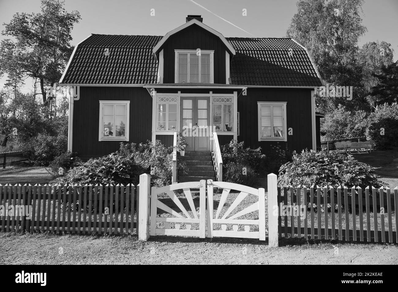 Schwedisch in schwarz-weiß Schuss. Tratitional Haus in Smalland, Weißer Zaun grünen Garten blauen Himmel. Kindheitserinnerungen aus dem Urlaub in Schweden. Entfällt Stockfoto