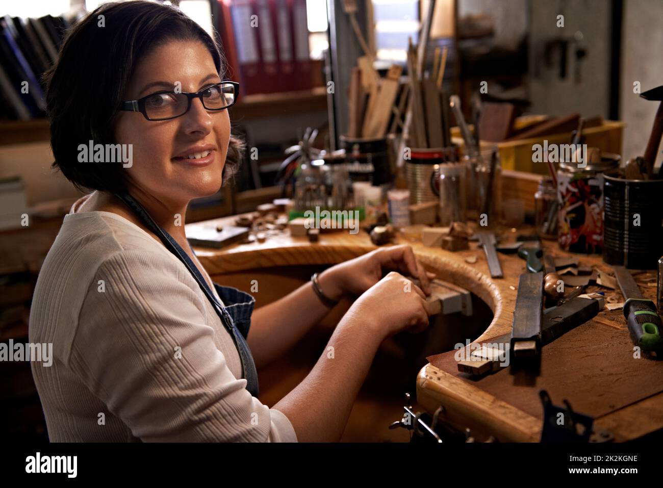 Kreativität bei der Arbeit. Eine glückliche junge Frau, die an einer Holzbearbeitungsbank arbeitet. Stockfoto