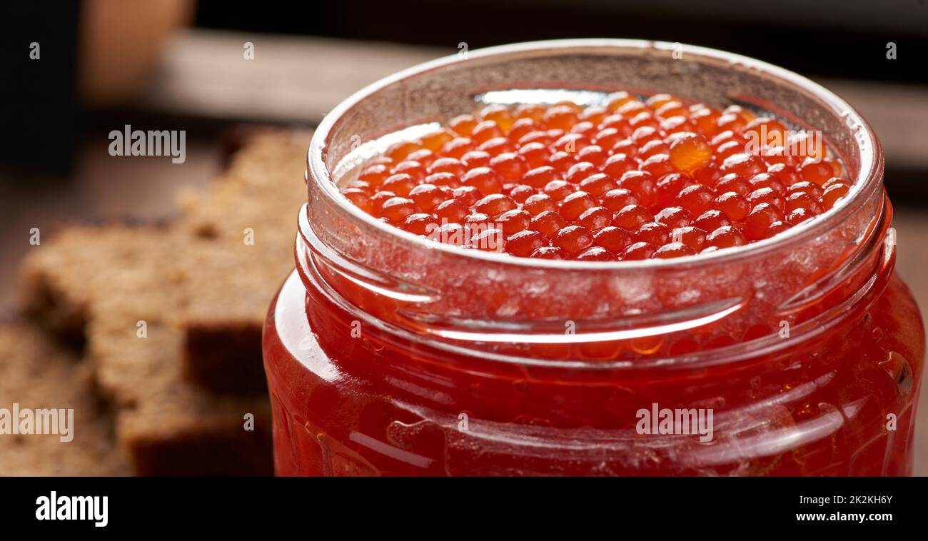 Glas aus Glas mit rotem Kaviar auf einem braunen Holztisch, Draufsicht Stockfoto
