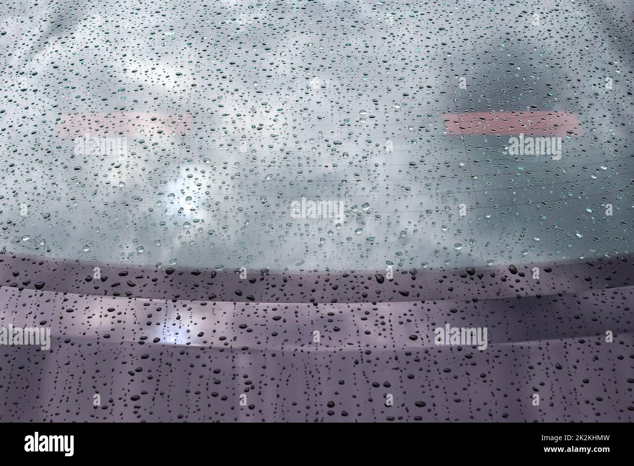 Regentropfen auf einer schwarzen Metalloberfläche in der Nahaufnahme. Stockfoto