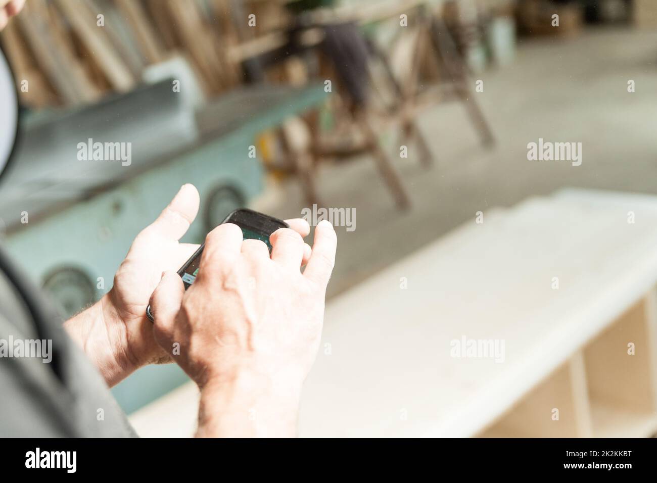 Die Hände eines Holzarbeiters mit einem Mobilgerät Stockfoto