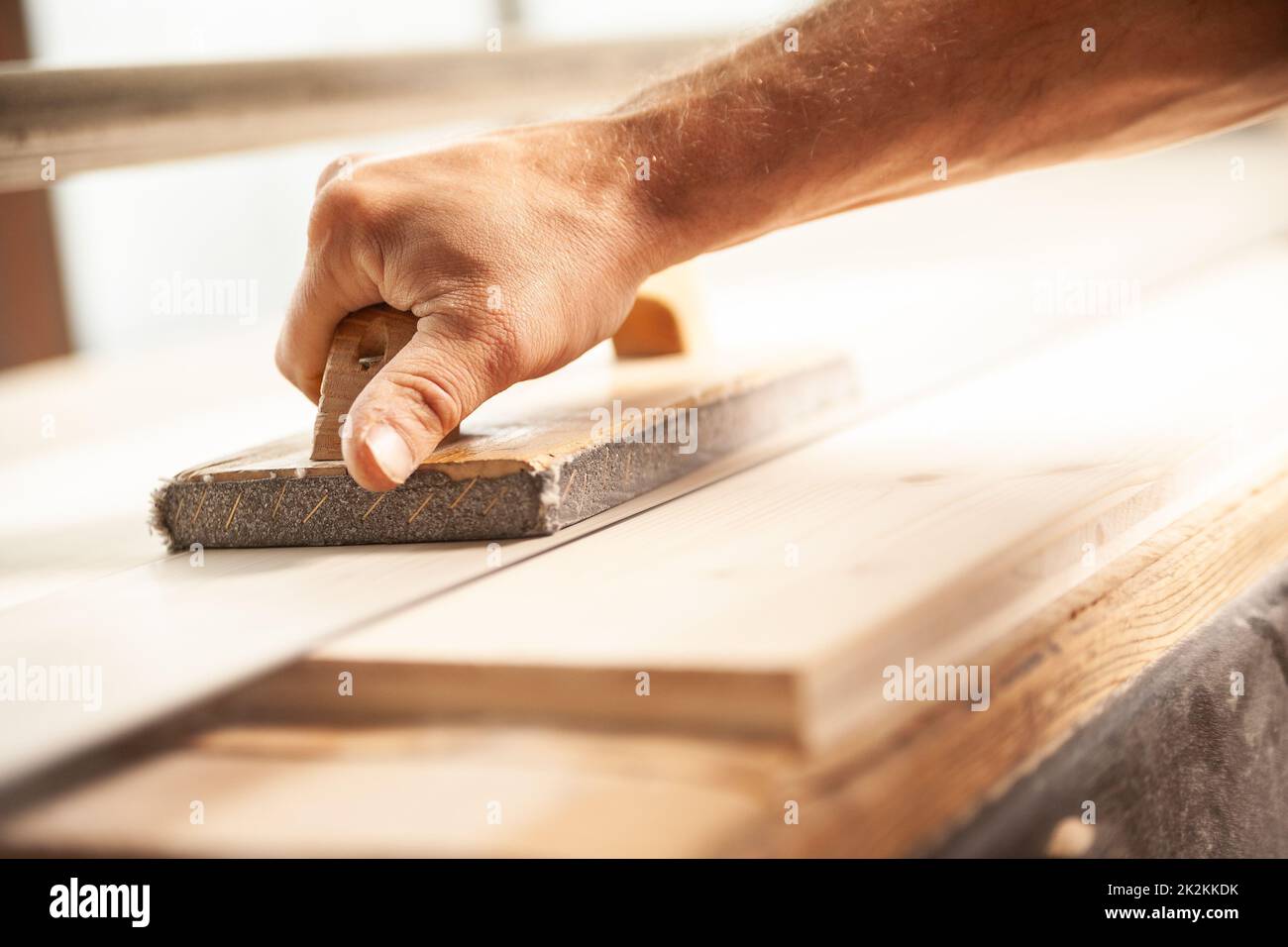 Zimmermann mit Schleifgerät in der Werkstatt zum Glätten von Holz Stockfoto