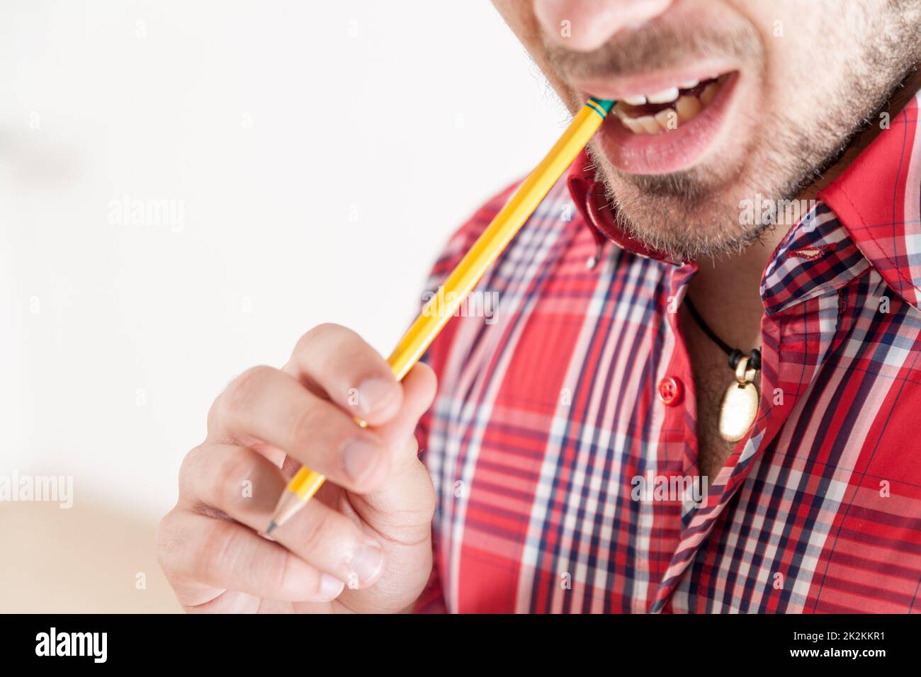 Ein Mann, der einen Bleistift hält und beißt Stockfoto