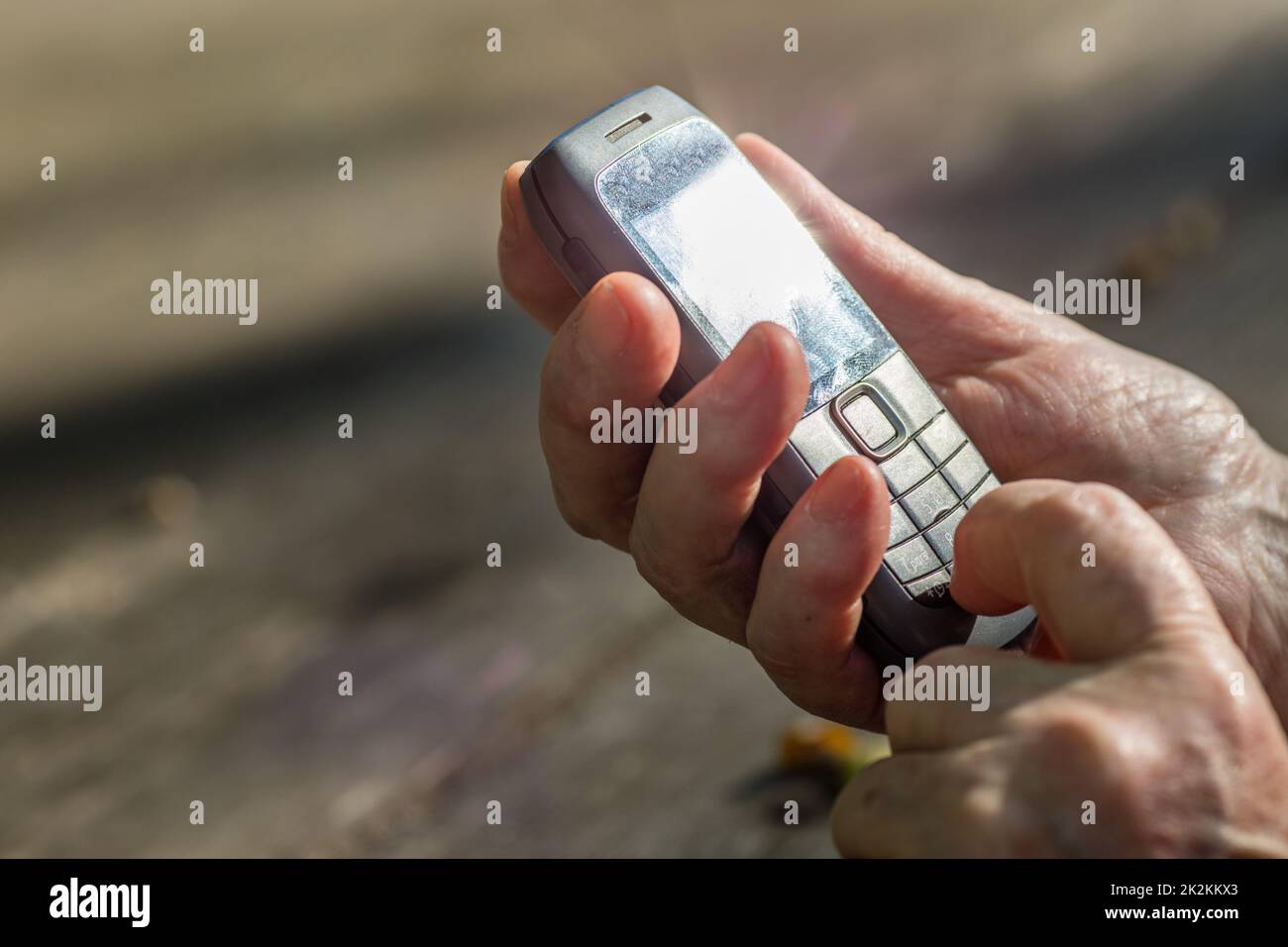 Finger einer alten Hand, der ein Mobiltelefon berührt Stockfoto