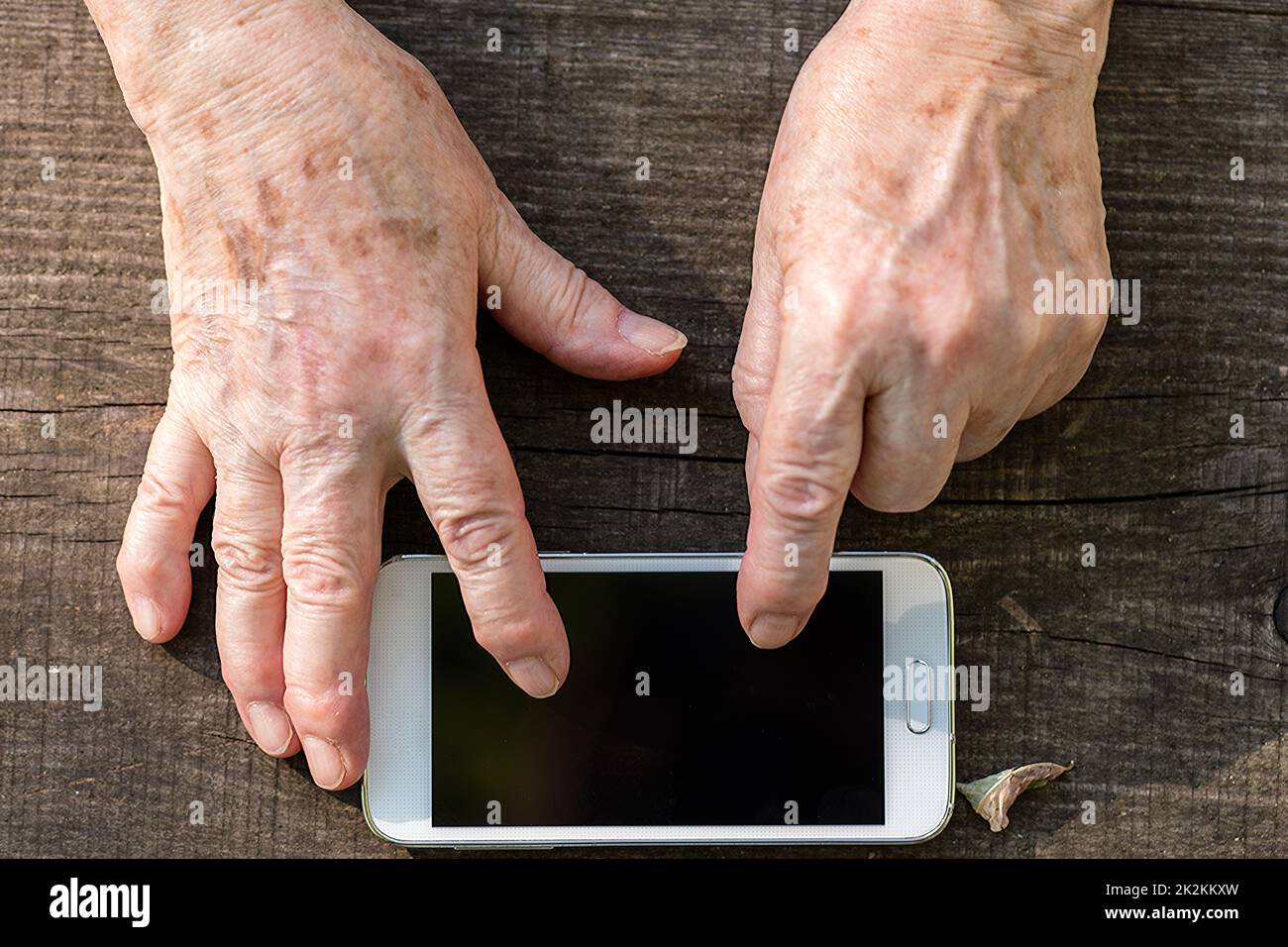 Ältere Hände über den Touchscreen eines Mobiltelefons Stockfoto