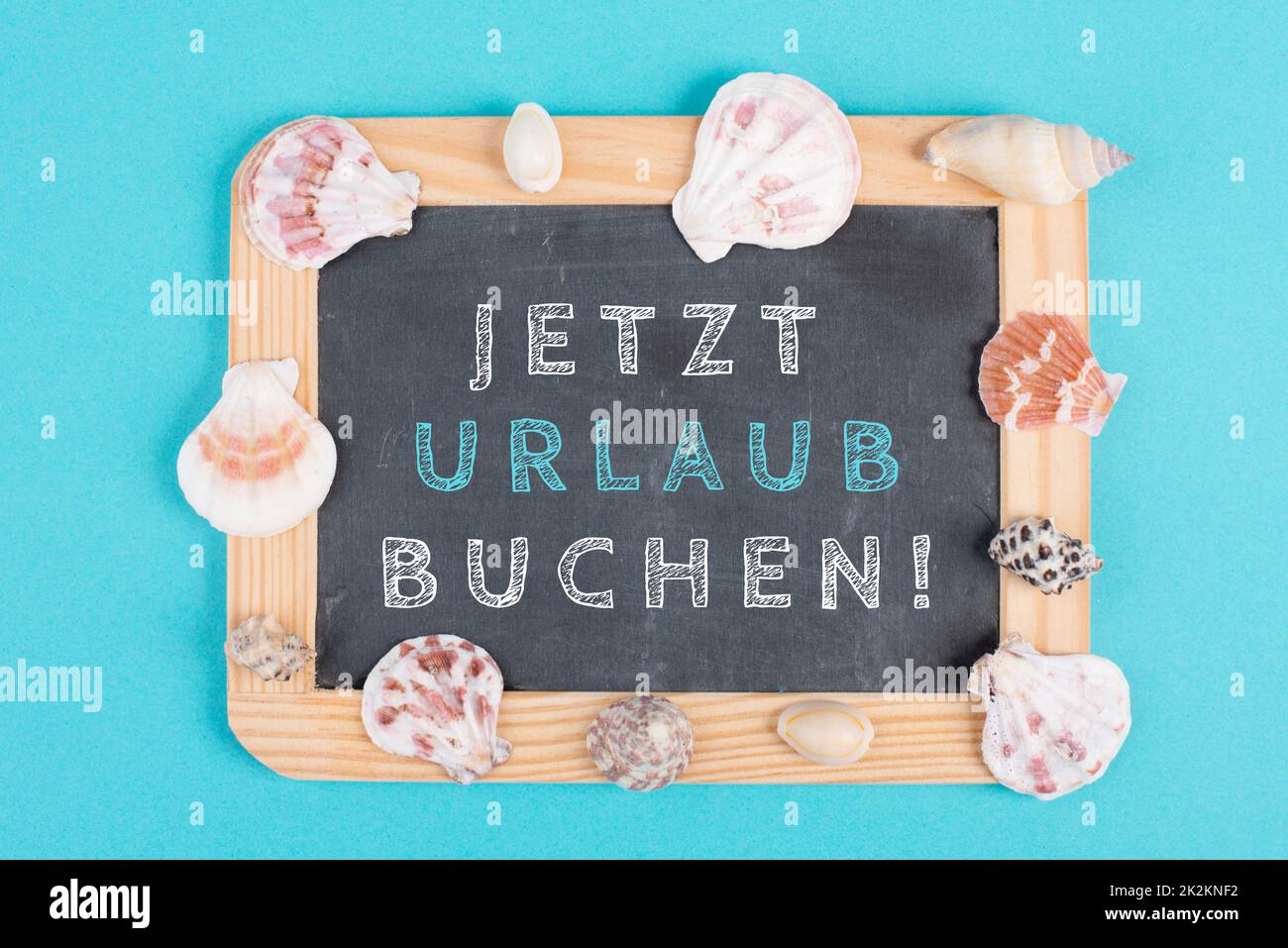 Jetzt buchen Urlaub steht in deutscher Sprache auf der Tafel, Muschelschalen, Urlaubs- und Sommerthema, Reisekonzept Stockfoto