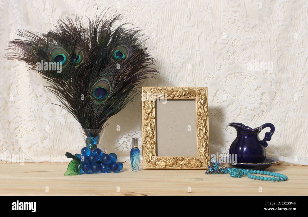 Vase mit Pfauenfedern, blauem Schmuck und goldenem Bilderrahmen Stockfoto
