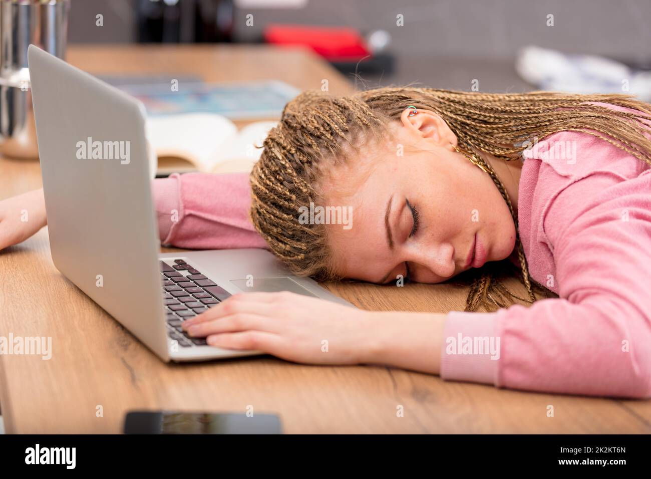 Erschöpfte junge Frau, die an ihrem Laptop schläft Stockfoto