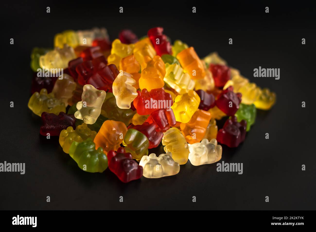 Ein Haufen Gummibären in verschiedenen Farben schoss Nahaufnahme auf schwarzem Hintergrund Stockfoto