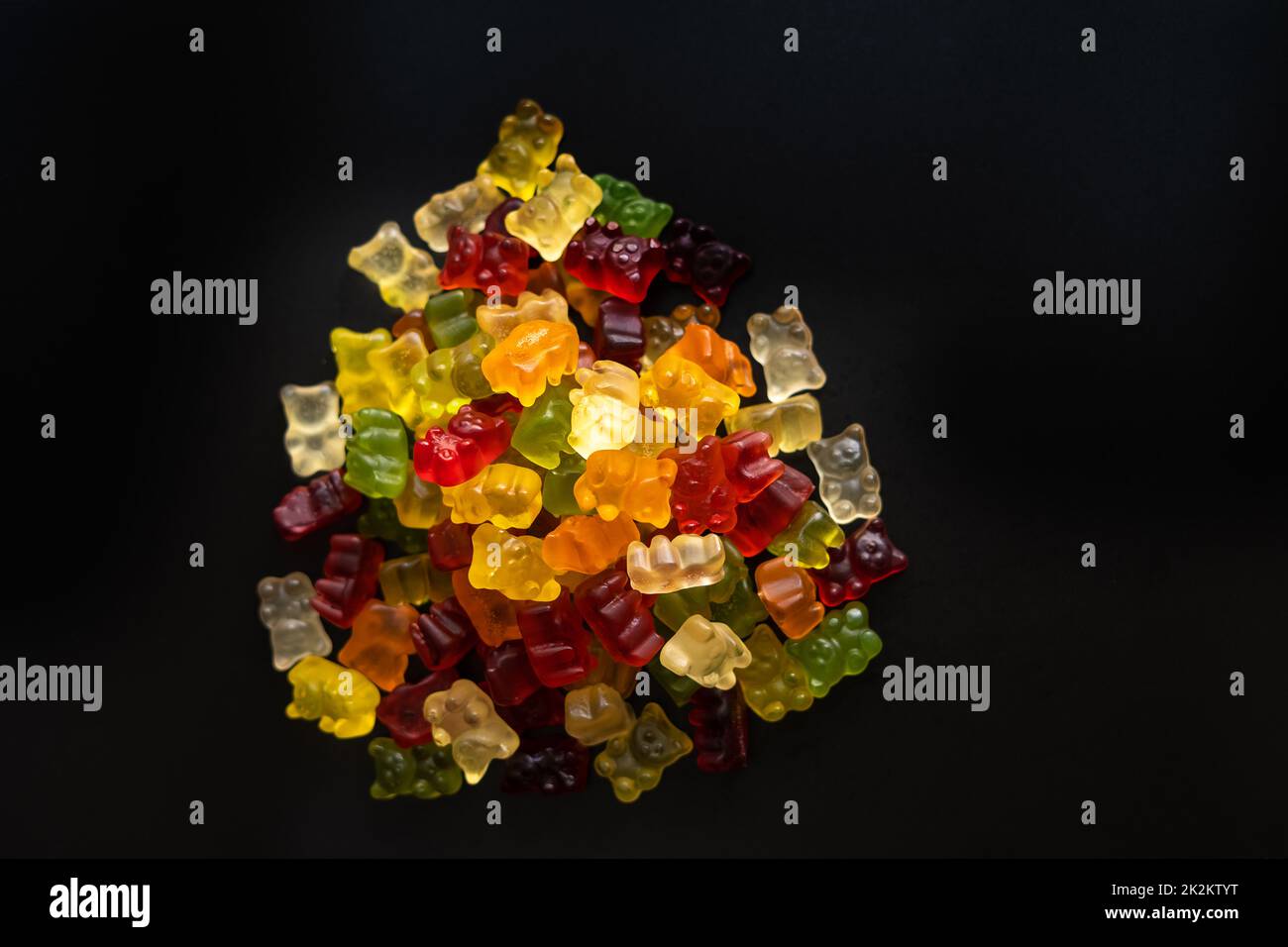 Draufsicht auf bunte Gummibären, die auf schwarzem Hintergrund dicht beieinander liegen Stockfoto