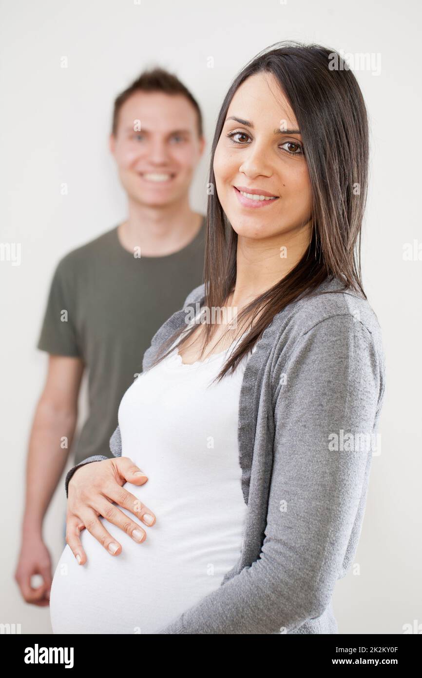 Schwangere junge Frau im Vordergrund mit Ehemann Stockfoto