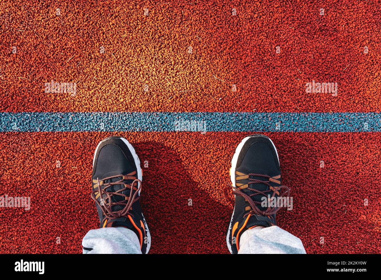 Füße in Sneakers stehen auf der Laufstrecke mit blauer Linie Stockfoto