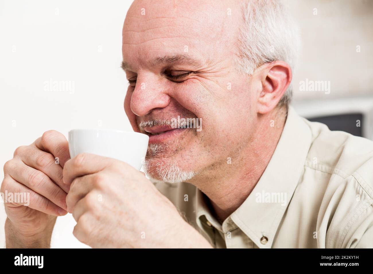 Ein grinsender Mann, der aus der Teetasse nippt Stockfoto
