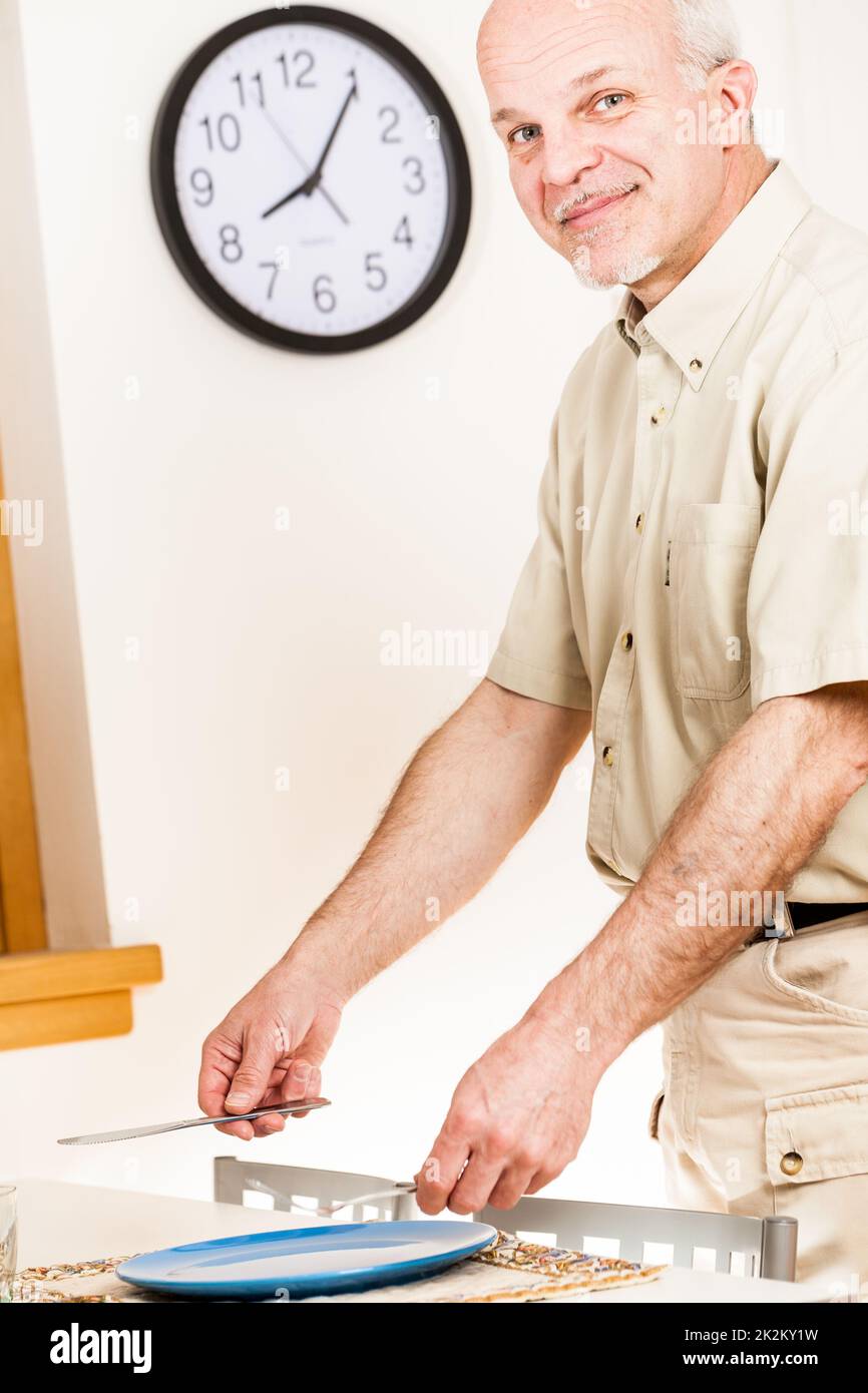 Ein Mann bereitet die Tischeinstellung für die Mahlzeit vor Stockfoto