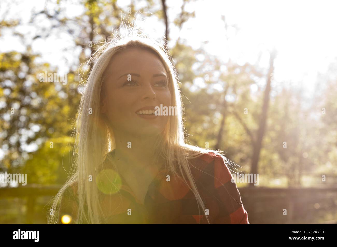 Blonde Frau mit Hintergrundbeleuchtung im Park Stockfoto