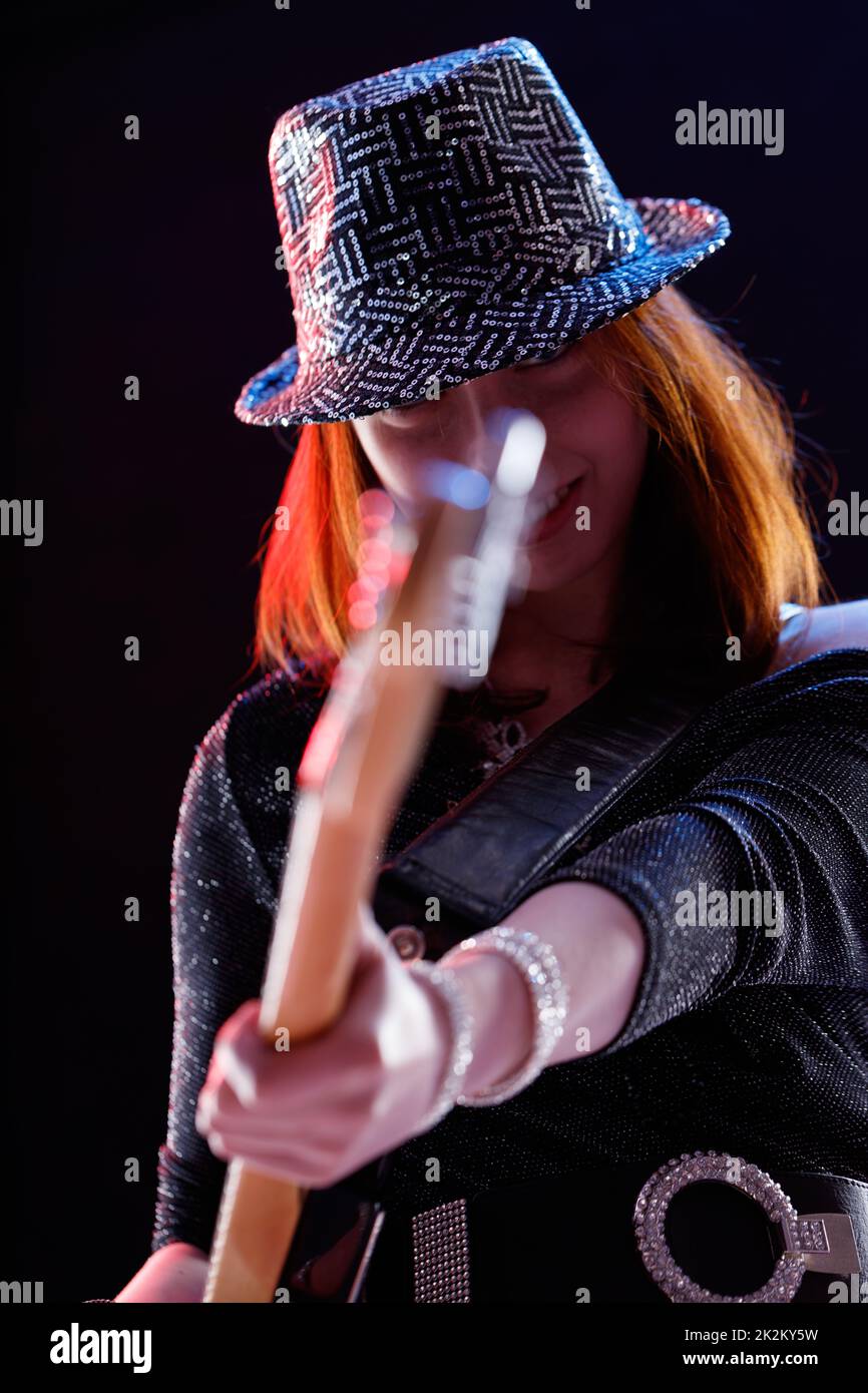 Trendige, stilvolle junge Musikerin, die Gitarre spielt Stockfoto