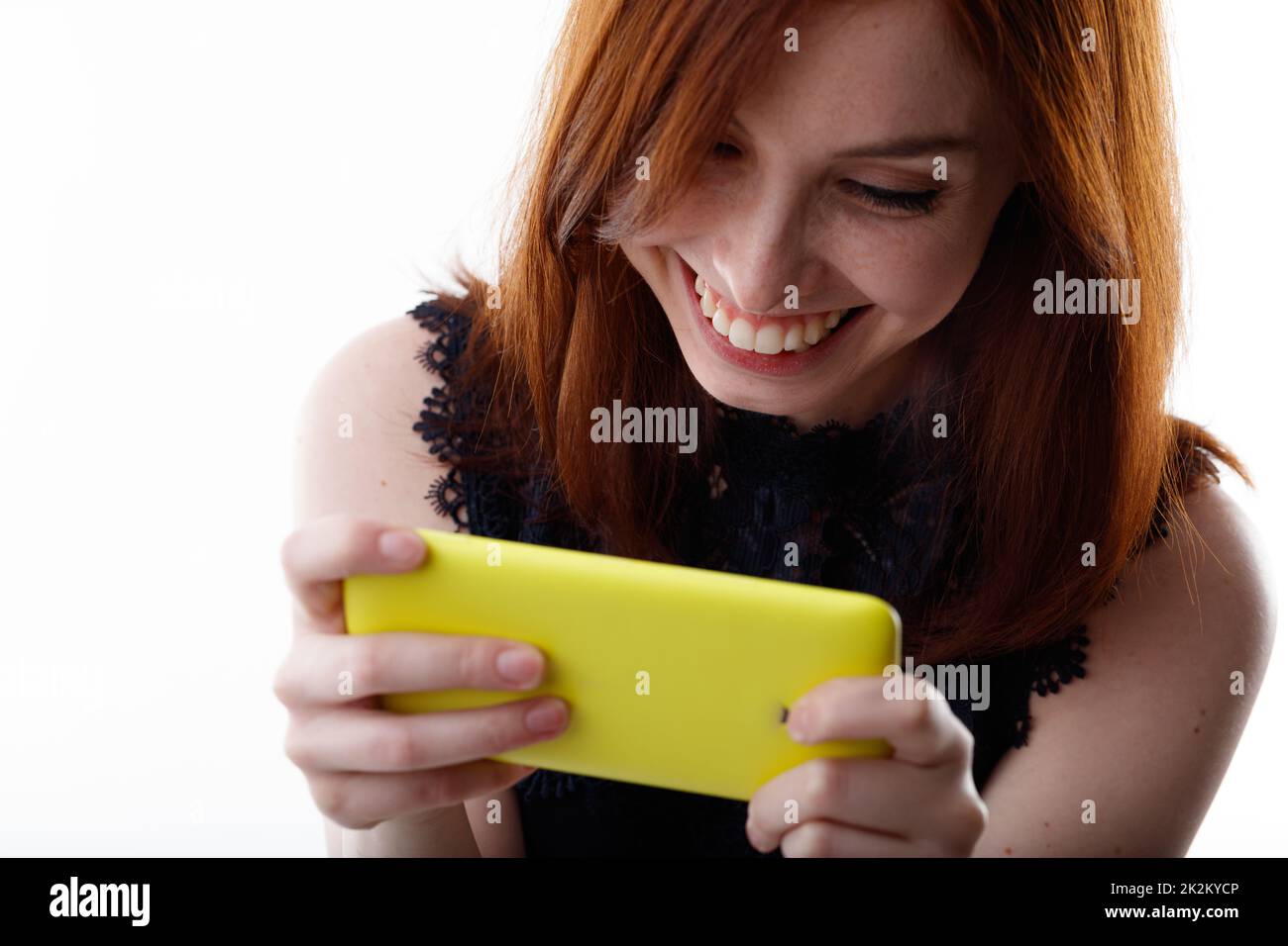 Glückliche Frau, die grinst, während sie Medien guckt oder eine Nachricht liest Stockfoto