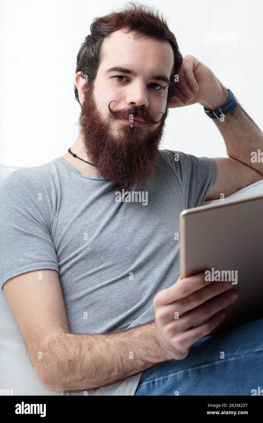 Hipster-Typ auf einem Sofa mit einem Tablet Stockfoto