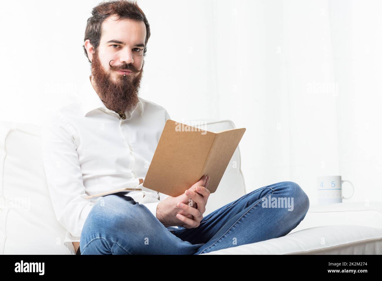 Entspannter Schüler liest in seinem Wohnzimmer Stockfoto