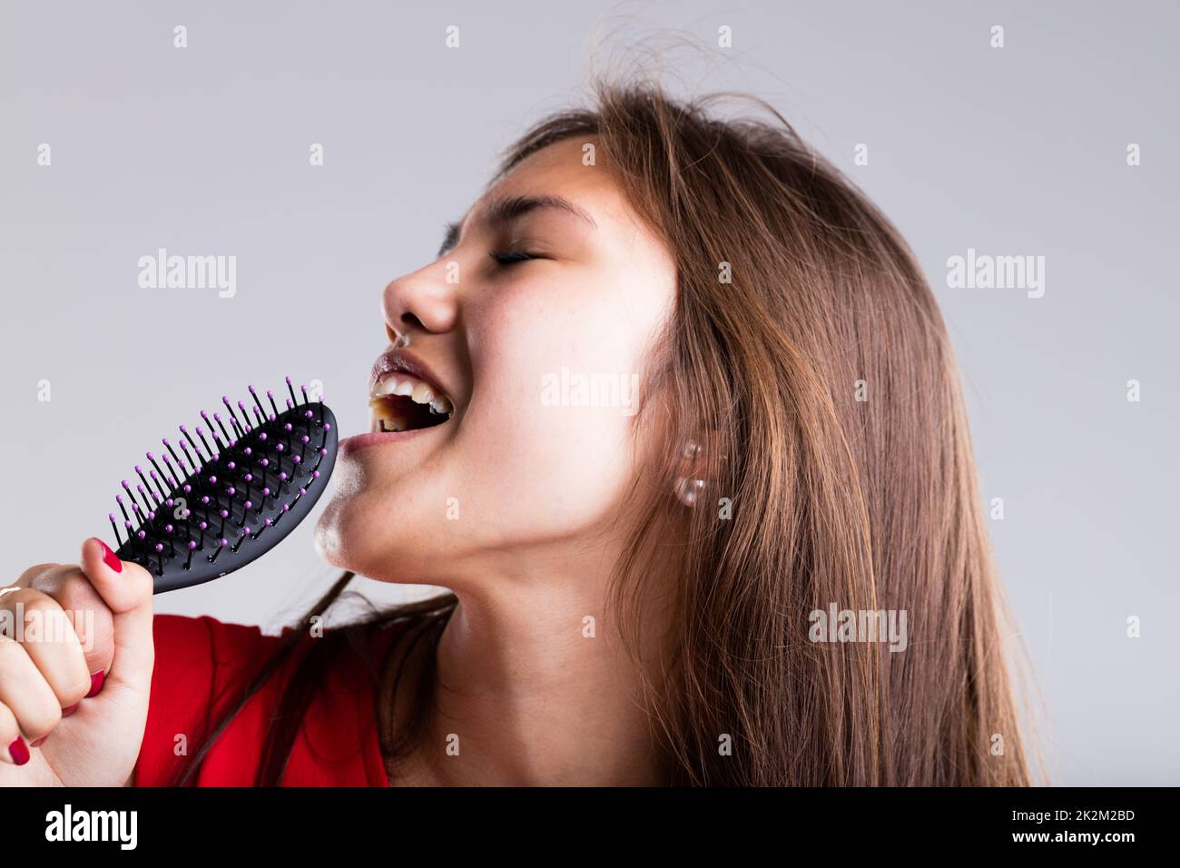 Leidenschaftliches Mädchen, das vorgibt, mit ihrer Haarbürste zu singen Stockfoto