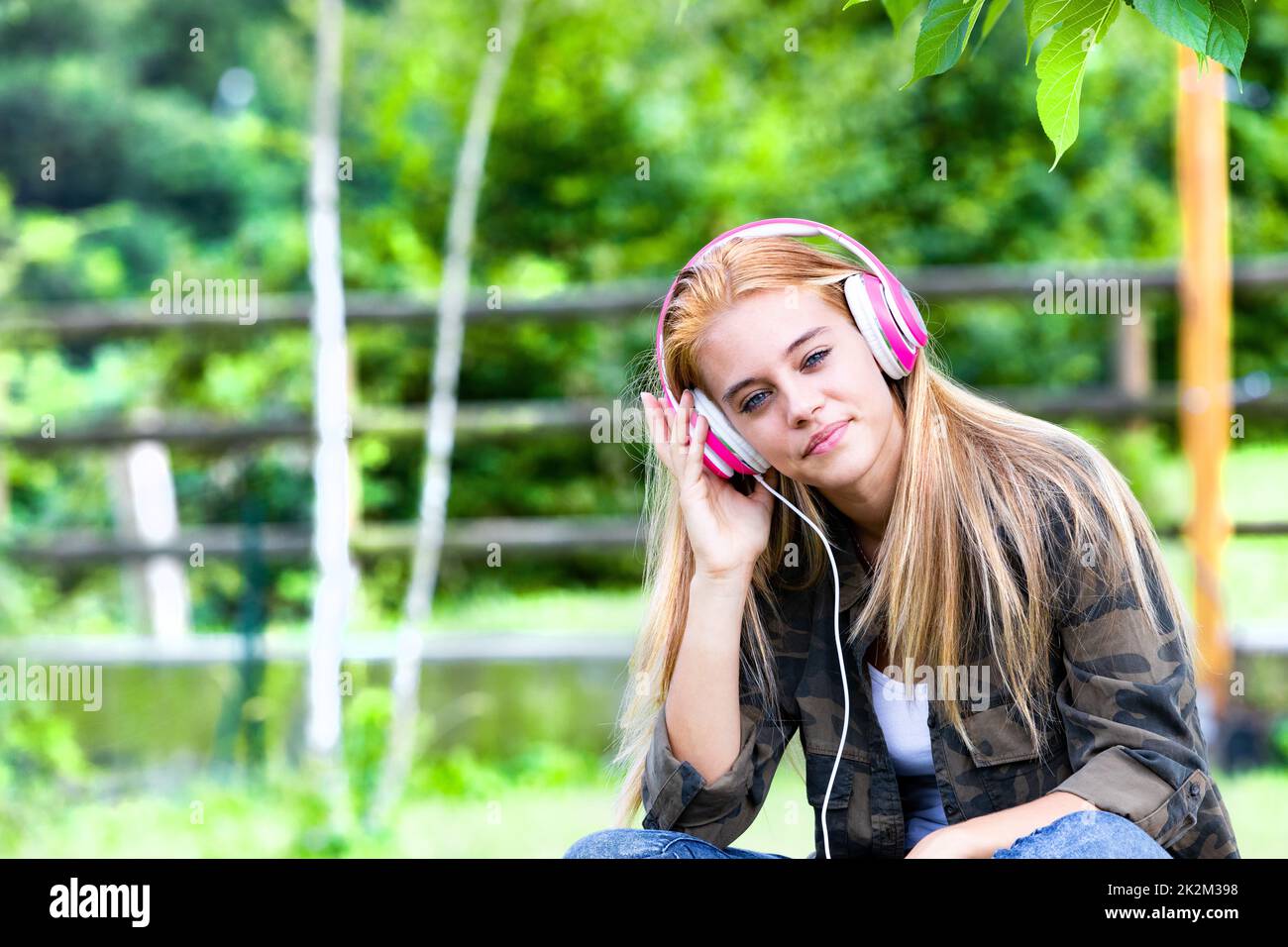 Blonde junge Frau, die Musik über Kopfhörer hört Stockfoto