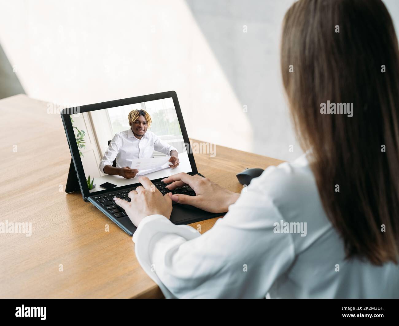Videoanruf. Remote-Arbeit. Digitales Meeting. Geschäftsfrau mit Laptop diskutiert Projekt online mit männlichem Partner auf dem Bildschirm im virtuellen Heimbüro. Stockfoto