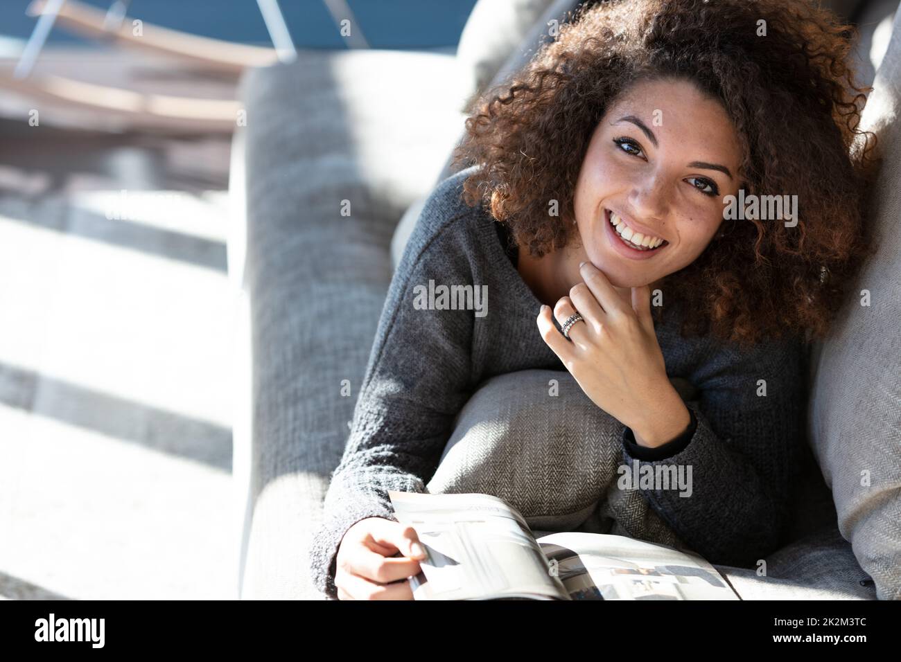 Glückliche Frau, die in der Lounge liegt und Magazin liest Stockfoto