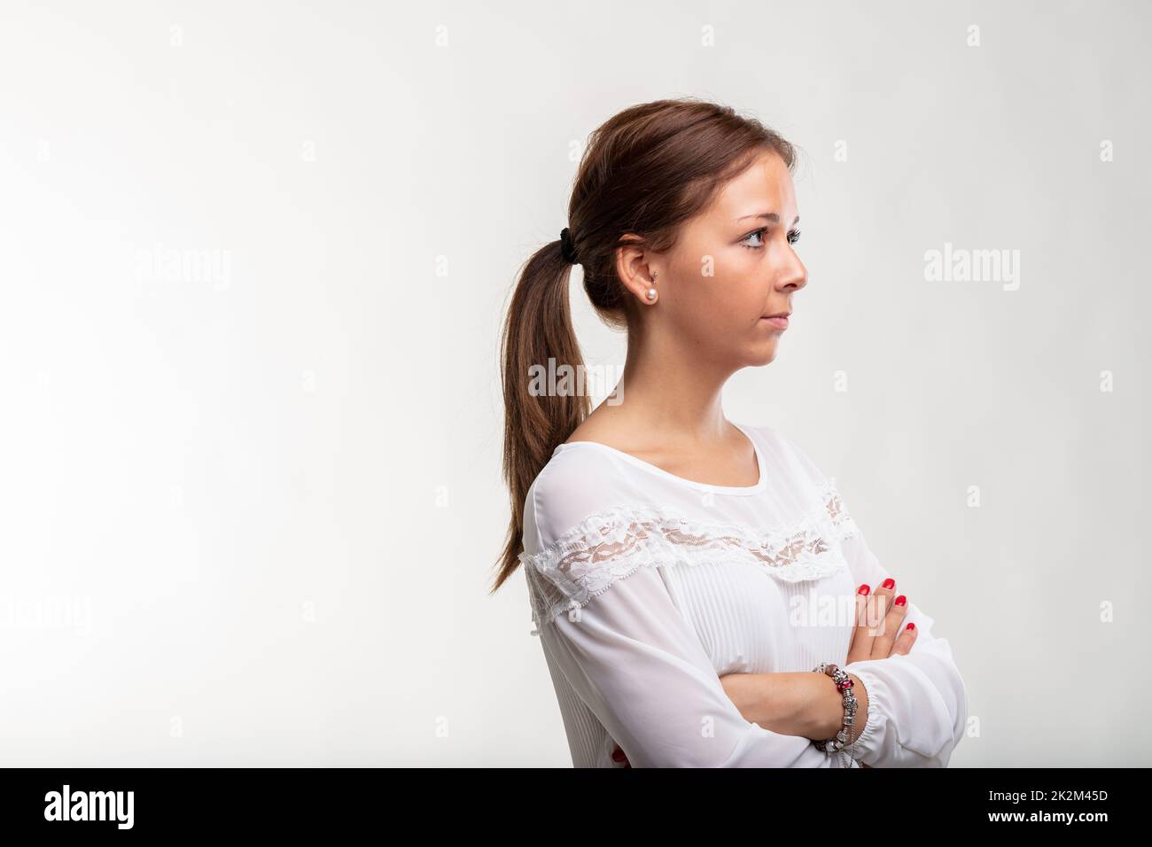 Selbstbewusste, ruhige junge Frau, die mit gefalteten Armen steht Stockfoto