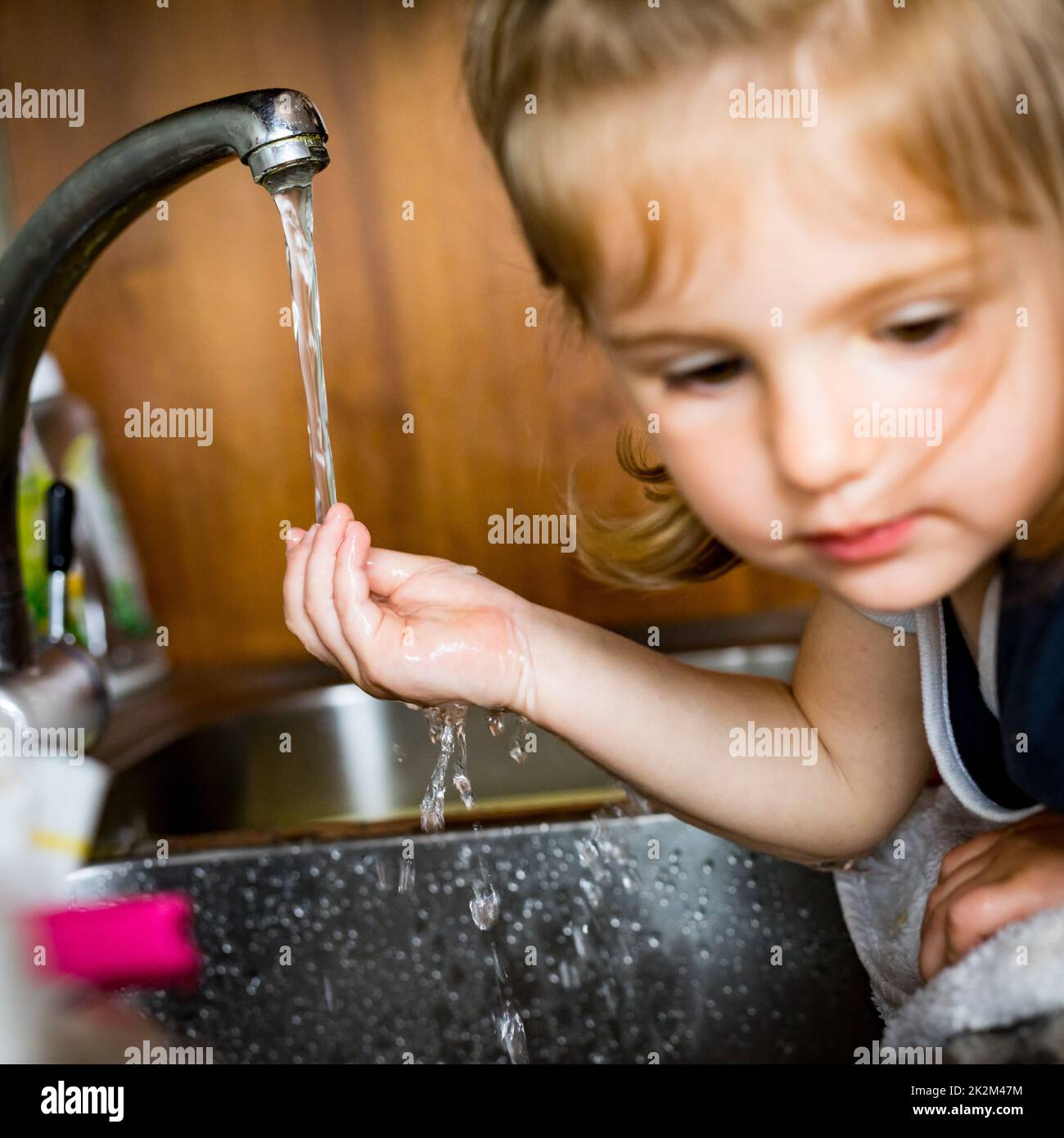 Kleines Mädchen mit der Hand unter Wasser Stockfoto