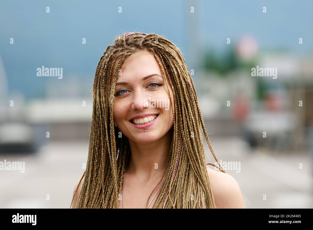 Lächelnde Frau in geflochtener Frisur im Freien Stockfoto