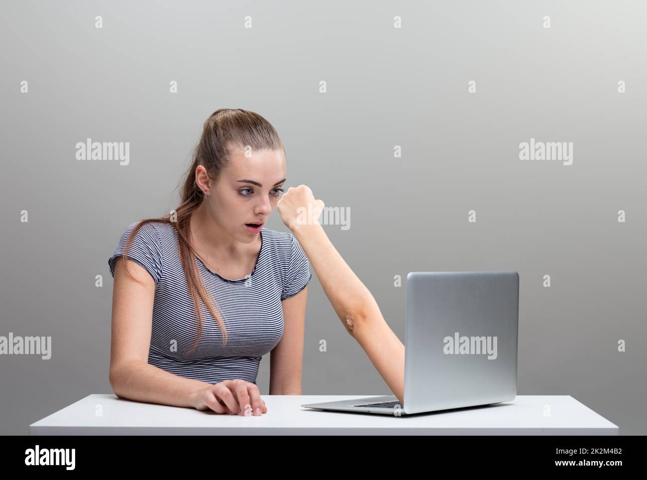 Frau, die Angst hatte, weil ein Arm aus dem Laptop ausstrebte Stockfoto