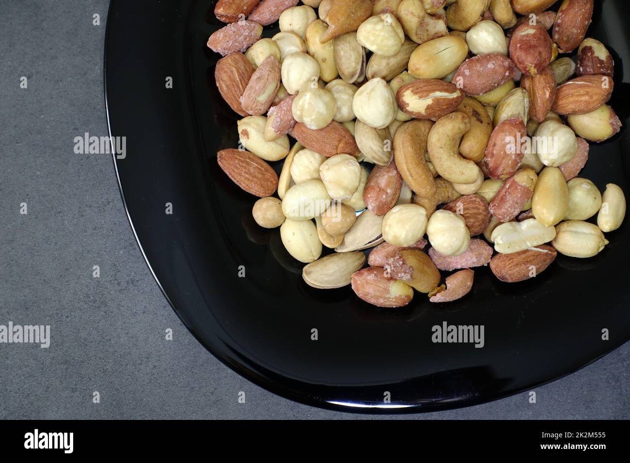 Es gibt eine Platte aus Nüssen, Haselnüssen, Erdnüssen, Cashewkernen auf dem Teller. Stockfoto