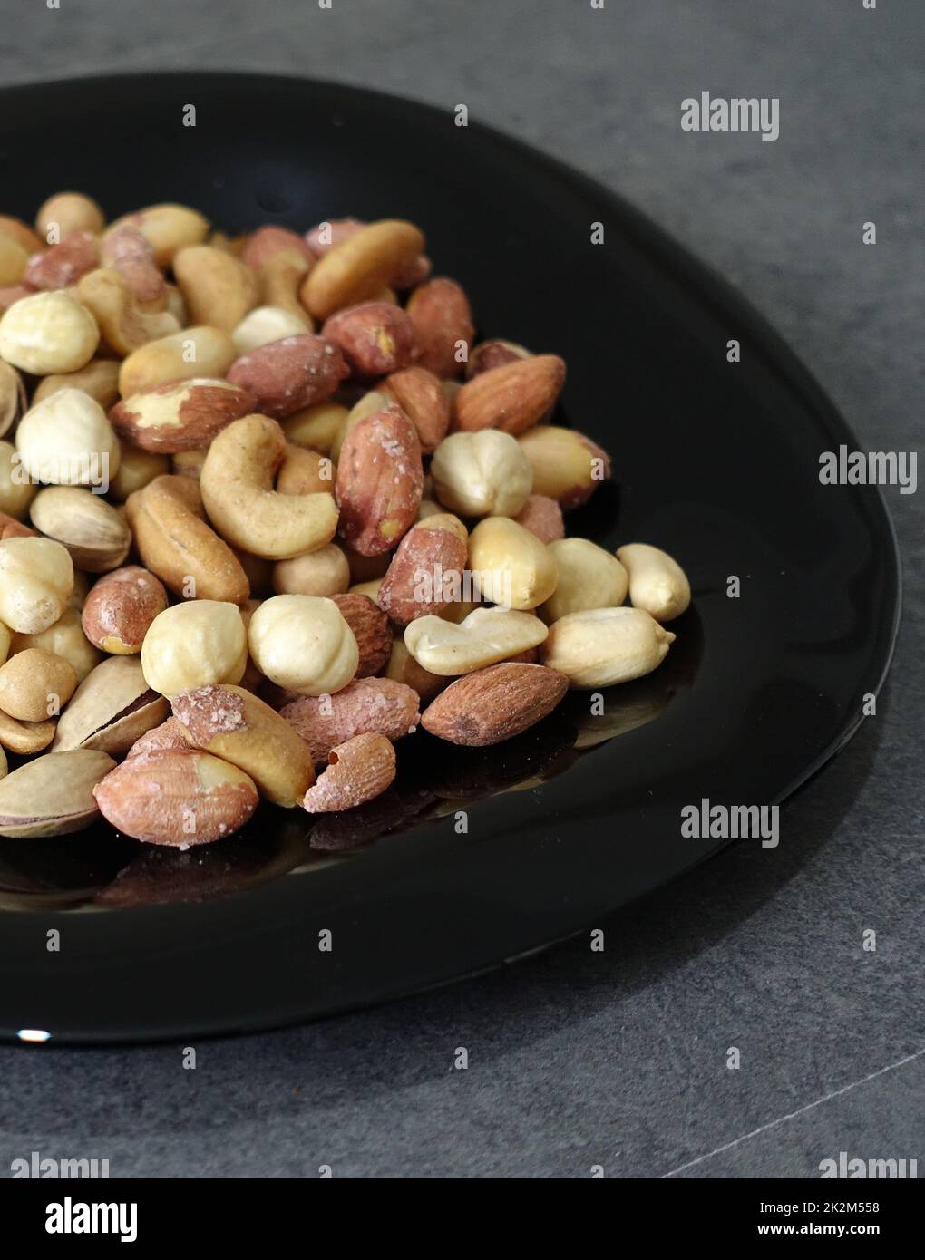 Es gibt eine Platte aus Nüssen, Haselnüssen, Erdnüssen, Cashewkernen auf dem Teller. Stockfoto