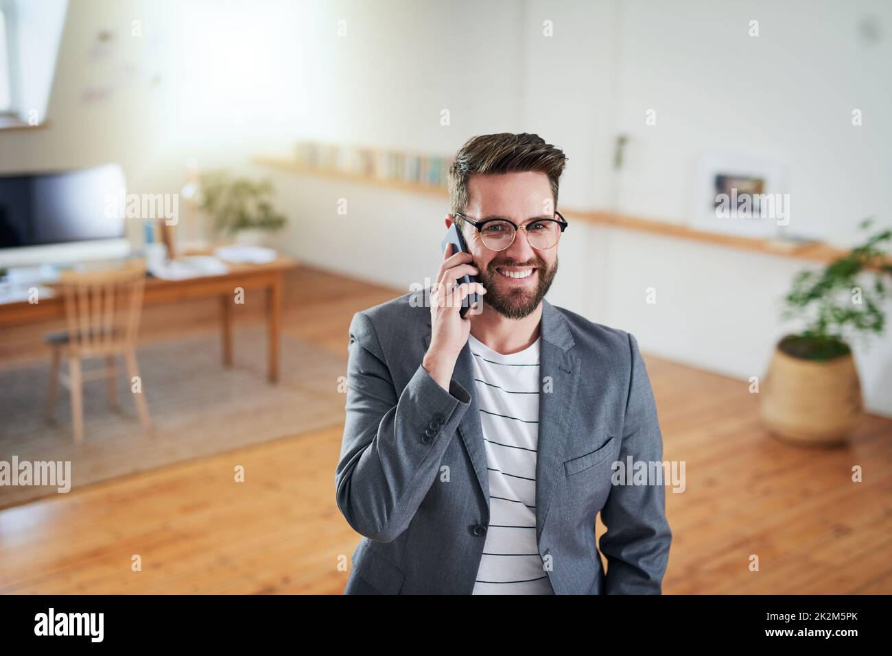 Erfolg beginnt mit Kommunikation. High-Angle-Aufnahme eines hübschen jungen Geschäftsmannes, der auf seinem Handy spricht, während er in seinem Heimbüro steht. Stockfoto