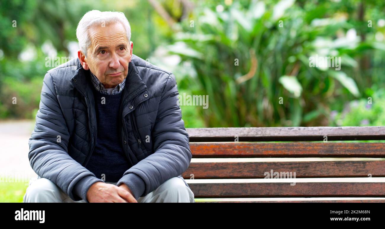 Und jetzt bin ich ganz allein. Ausgeschnittene Aufnahme eines sorglosen älteren Mannes, der auf einer Bank saß, während er draußen in einem Park nachdachte. Stockfoto