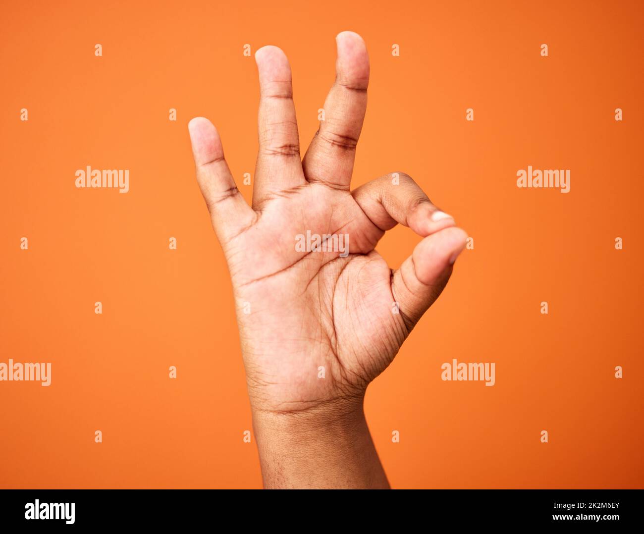 Alles wird in Ordnung sein. Aufnahme einer nicht erkennbaren Person, die eine Handbewegung vor einem orangefarbenen Hintergrund zeigt. Stockfoto