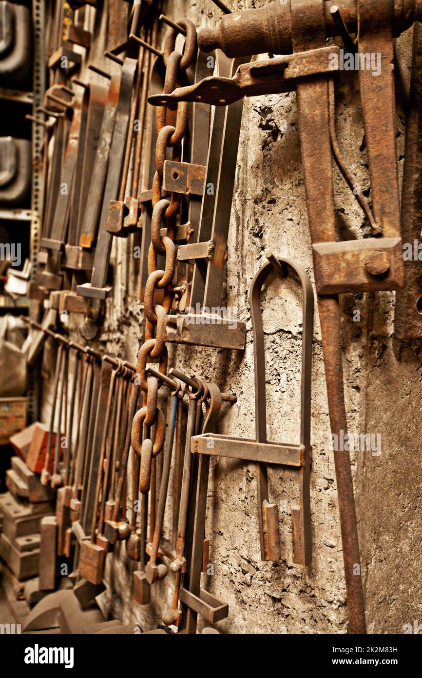 Vintage-Werkzeuge für den Vintage-Handwerker. Eine Reihe gut verwendeter Werkzeuge, die an einer strukturierten Wand hängen. Stockfoto