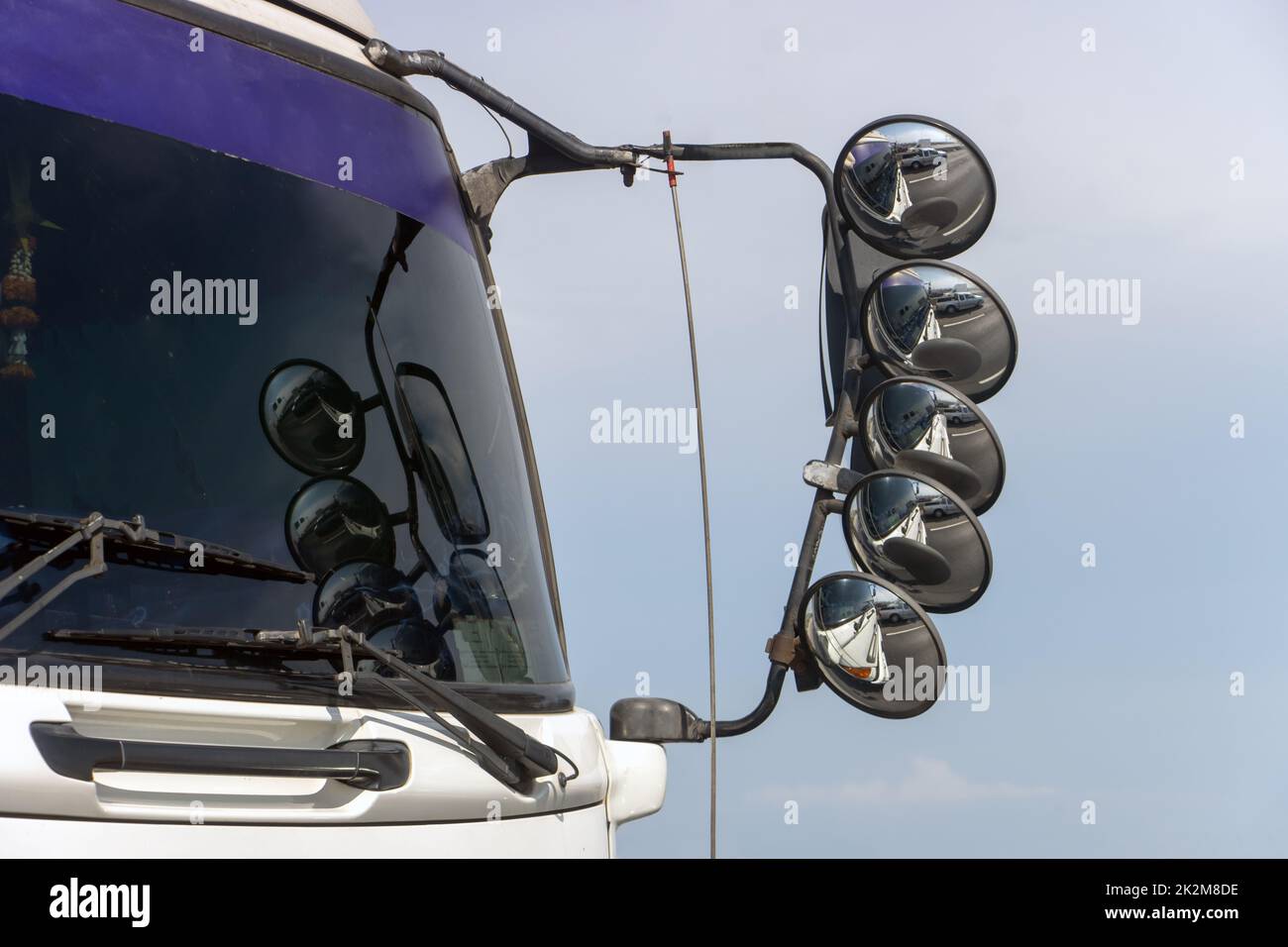 Die Stahlhalterung mit Rückspiegeln, die an der Kabine des Lkw angebracht sind, der auf der Autobahn unterwegs ist. Stockfoto